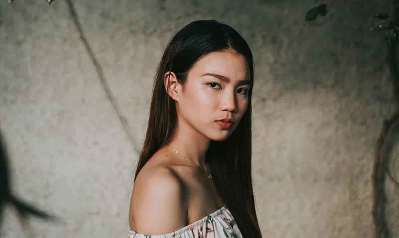 Headshot of Hulda Nuh, a young Asian woman with short blonde hair, wearing a black bucket hat.